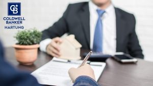 two people, faces not shown, working on a home contract to sell a home