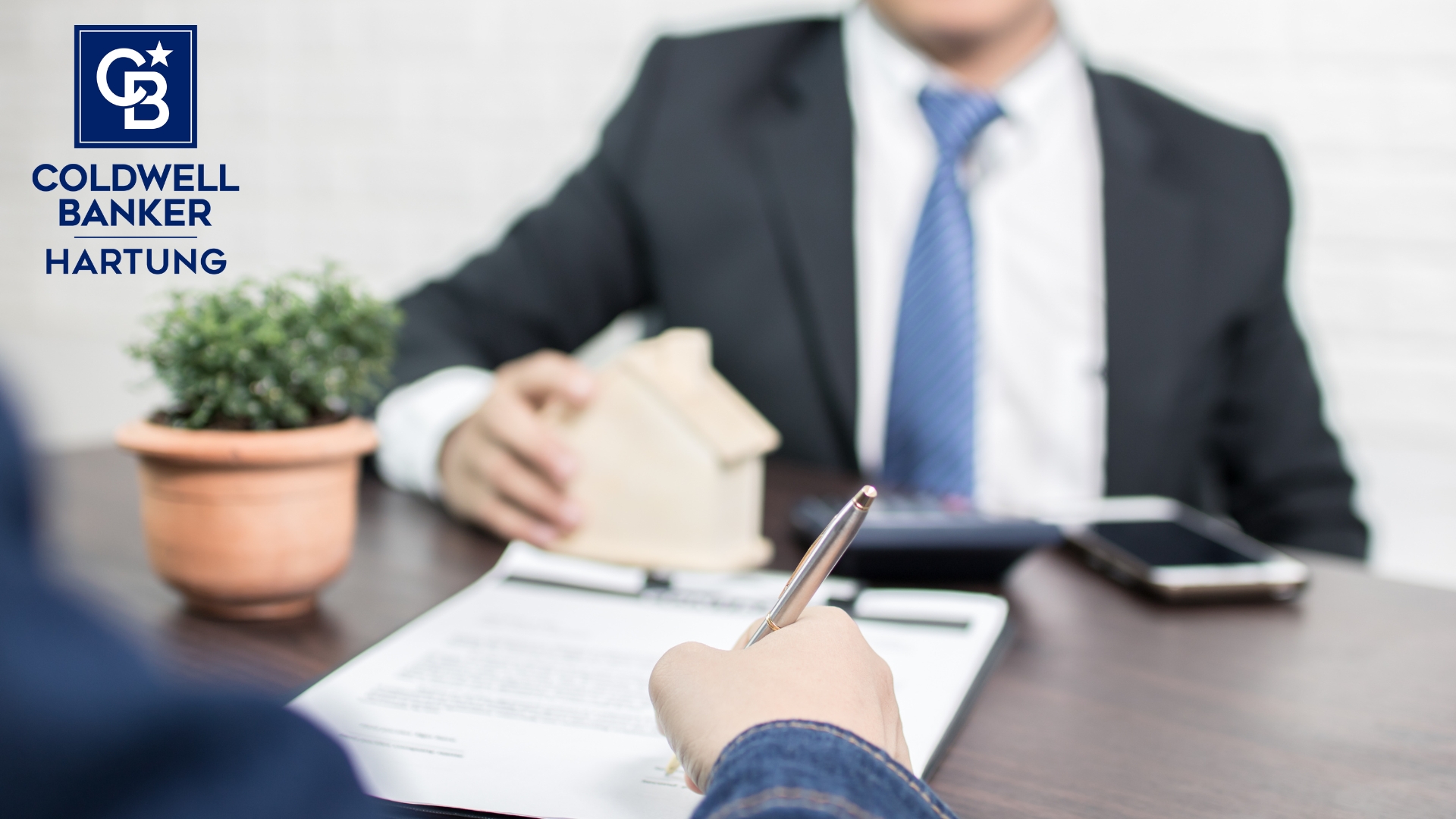 two people, faces not shown, working on a home contract to sell a home